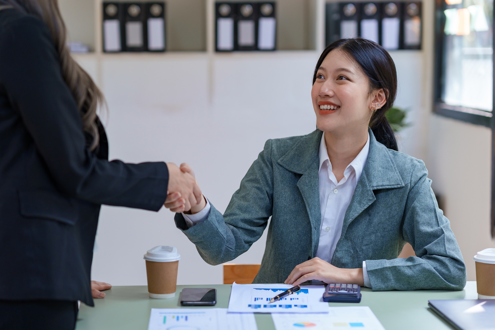 Businesswomen shaking hands to congratulate on mutual business agreement.