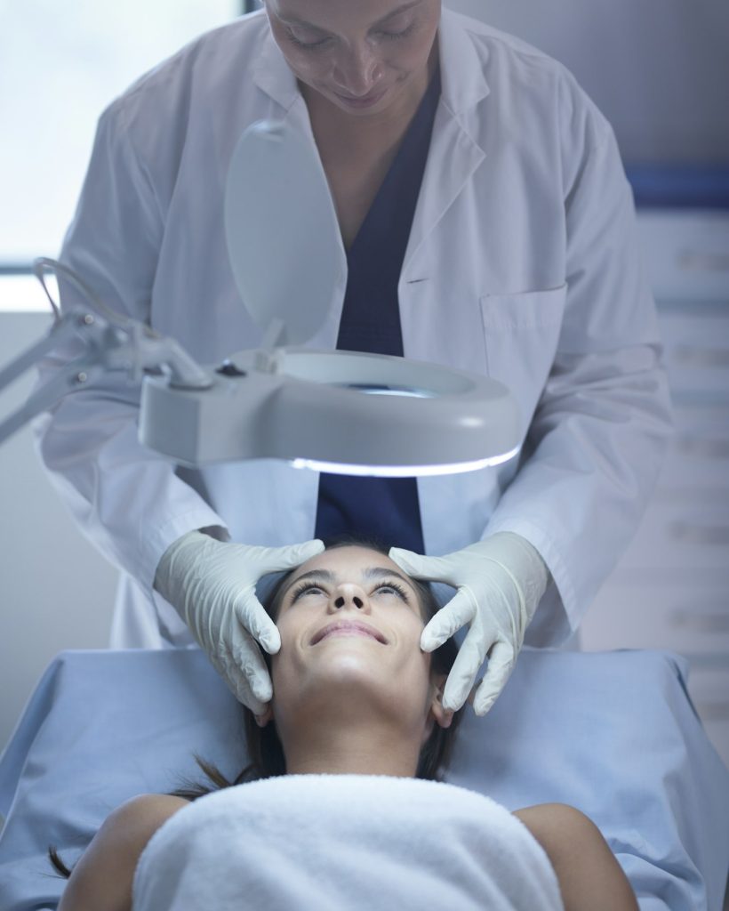 Front view of a female surgeon examining her Caucasian patient during plastic surgery in clinic